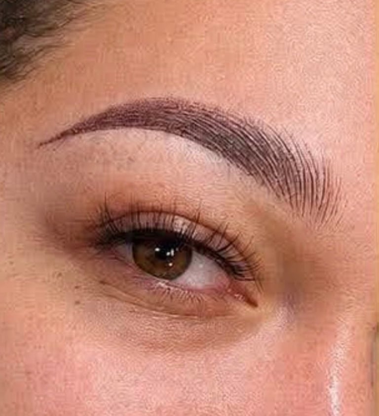 Close-up of a womans eye with brown iris, defined eyebrow, and dark eye makeup applied