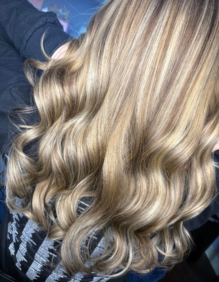 Foil highlight and lowlight hair color at CC Styling Studio in Bradenton, FL — long wavy blonde hair with highlights styled in loose waves and curls