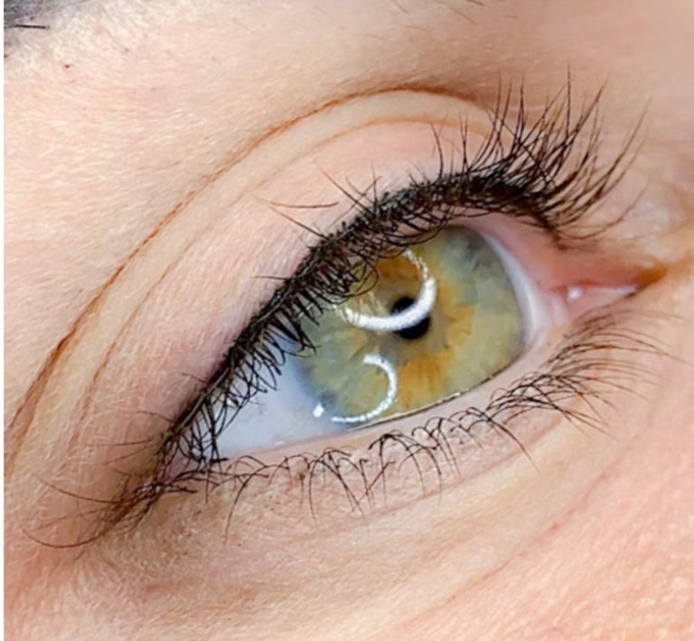 Close-up of a persons eye with golden-brown iris, black eyeliner, and thick black eyelashes at CC Styling Studio Bradenton FL