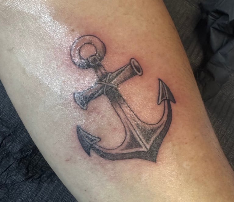 Black and gray anchor tattoo on a person's forearm with rope detailing