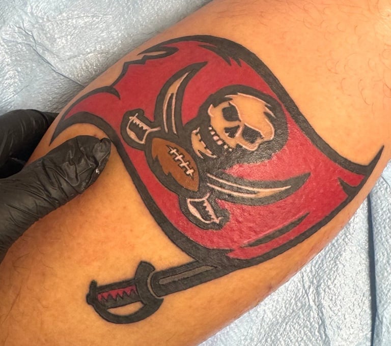 Tattoo of a red pirate flag with skull and crossed sword on someone's arm
