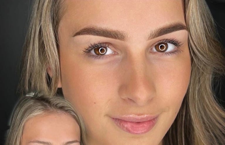 Close-up portrait of a woman with long ash-blonde hair, defined eyebrows, and neutral makeup against a dark background