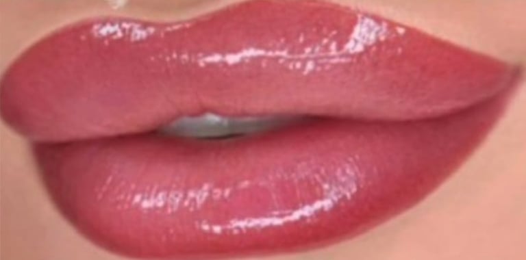 Close-up of glossy mauve-pink lipstick applied to lips with smooth, shiny finish