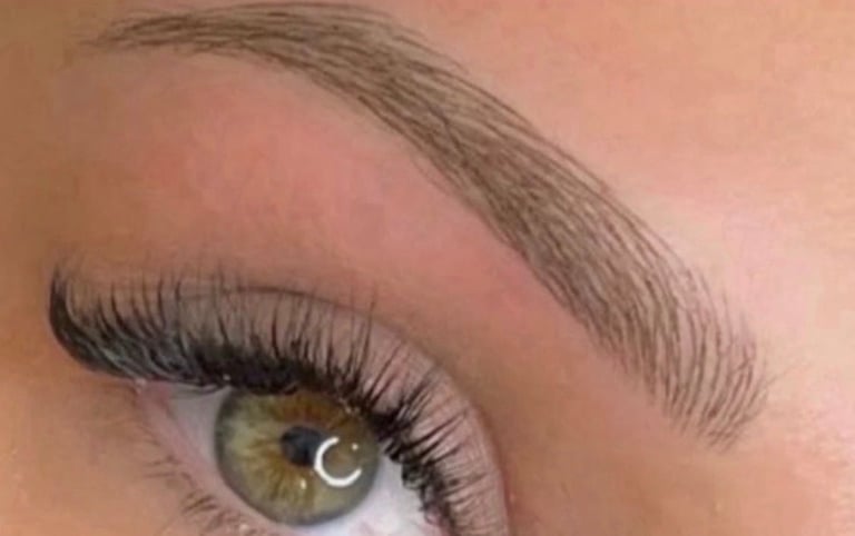 Close-up of an eye with defined makeup, featuring black eyeliner, dark mascara on lashes, and a hazel iris with light reflection