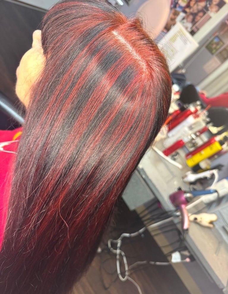 Chunky red lowlights at CC Styling Studio in Bradenton, FL — close-up of long hair with red and dark striped highlights in a salon setting