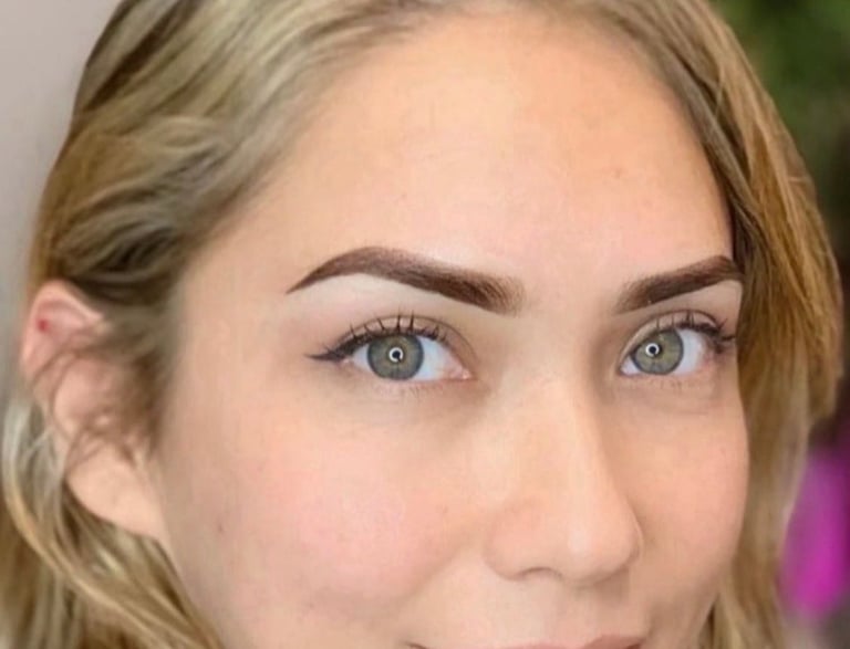 Close-up portrait of a woman with blonde hair, light eyes, and defined eyebrows looking directly at camera